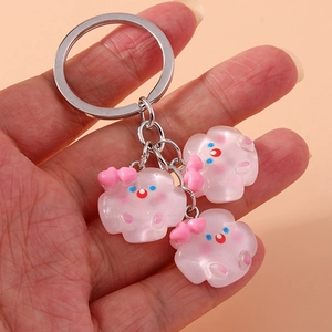 Détail de trois breloques nuages en résine rose avec nœuds sur un porte-clés argenté