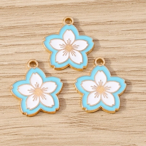 Three elegant cherry blossom enamel pendants on light wood background for DIY jewelry