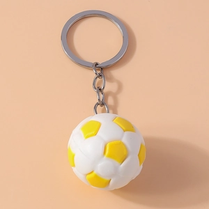 Macro detail of yellow and white soccer ball keychain with silver metal ring and chain