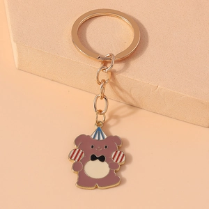 Detailed close-up of cartoon bear enamel keychain with gold ring and party hat accessory