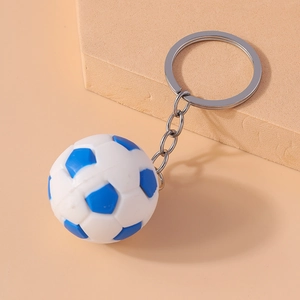 Detail view of a white and blue miniature soccer ball keychain on a geometric stand