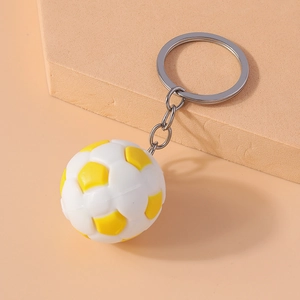 Detail of a yellow and white soccer ball keychain with a silver metal link and ring