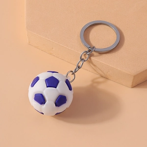 Detailed view of realistic soccer ball keychain with silver chain on orange surface