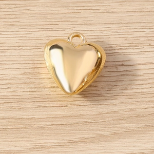 Close-up of heart-shaped gold metal pendant with polished finish and circular ring connector