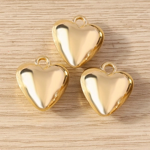Three gold 3D heart pendants with mirror finish on a wood background, minimalist jewelry DIY