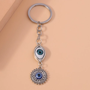 Hiphop Evil Eye keychain with sun pendant and blue bead on minimalist pink background