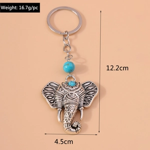 Detail of vintage silver elephant keychain with turquoise beads and engraved patterns