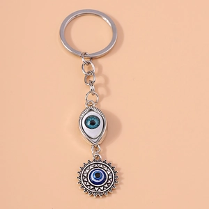 Detail of silver alloy evil eye keychain with sun pendant on pink background
