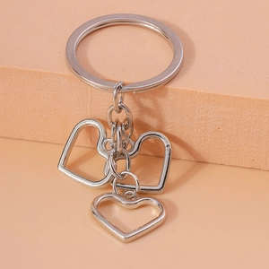 Close-up of a silver hollow heart-shaped keychain with three small charms and a ring