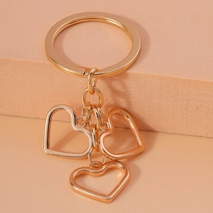 Detail of three hollow heart-shaped pendants hanging from a gold-toned metal keychain