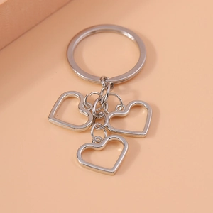 Detail view of silver hollow heart keychains with polished metal finish on orange surface