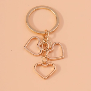 Detailed view of polished gold alloy keychain with three hollow heart pendants on ring