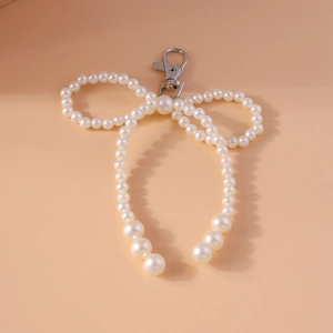 Detail of beaded pearl bow pendant with silver lobster clasp on soft pink background
