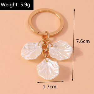 Detail of elegant pearl shell charms on a gold keychain with dimensions and weight info
