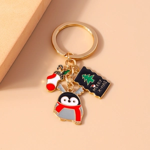 Christmas keychain with red sock, cute penguin and Merry X-mas tag on pink background