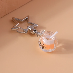 Detailed view of creative luminous coffee cup keychain with star clip and orange liquid