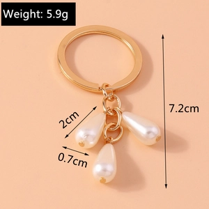 Detail view of a gold keychain with three white teardrop pearl pendants and size specs