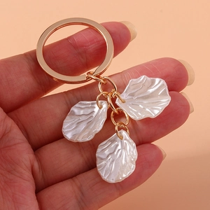 Close-up of golden keychain featuring elegant white pearlescent wave texture pendants