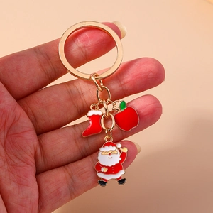 Hand holding cute Christmas keychain with Santa, red apple and stocking charms