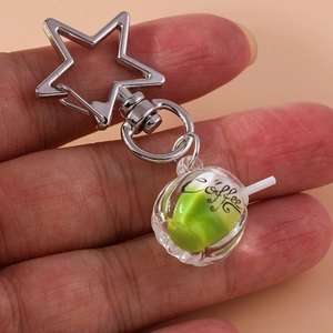 Detail of creative star-shaped metal clasp and glowing miniature green coffee cup keychain
