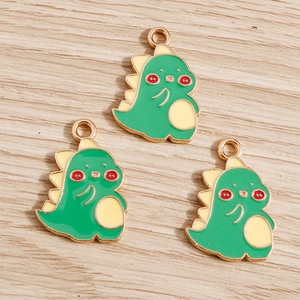 Detailed view of three cute green cartoon dinosaur enamel charms for DIY jewelry making