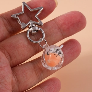 Detailed close-up of a creative luminous coffee cup keychain with orange liquid inside