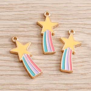 Close-up of enamel rainbow shooting star charms on a light wood background for DIY