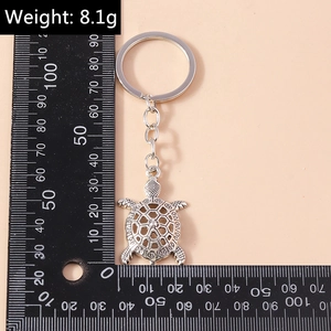 Silver metal turtle keychain detail showing intricate hollow shell texture and size scale