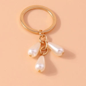 Detail of elegant gold metal keyring with three lustrous white teardrop pearl pendants