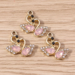 Détail de pendentifs cygne en cristal rose avec base dorée et strass brillants pour DIY