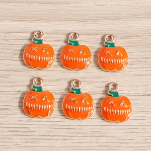Vue détaillée des breloques citrouilles en émail orange avec bords dorés pour bijoux Halloween