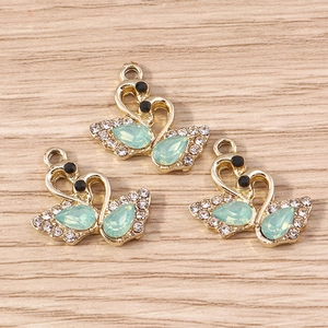 Détail de pendentifs en forme de cygne avec pierres vert clair et strass brillants