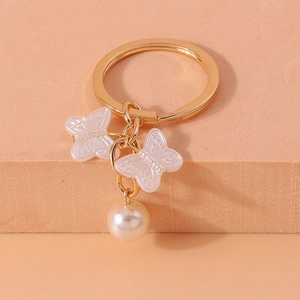 Detail view of pearl butterfly keychain with golden ring and translucent resin pendants