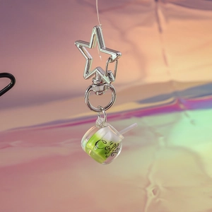Macro detail of a luminous mini coffee cup keychain with a silver star-shaped clasp