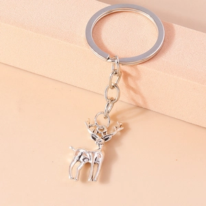 Porte-clés élan en métal argenté poli sur un présentoir rose au style minimaliste