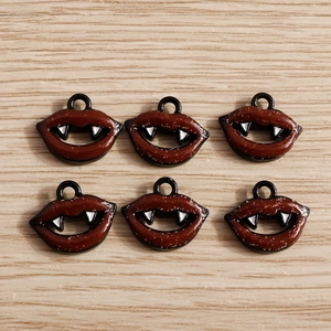 Vue détaillée de pendentifs lèvres de vampire pour Halloween en émail rouge et blanc