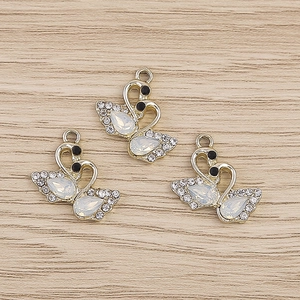 Pendentifs cygne élégants avec base dorée et cristaux blancs sur fond de bois