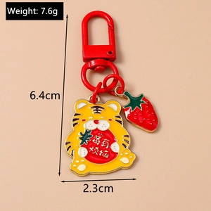 Détail du porte-clés tigre jaune de 6,4 cm avec breloque fraise et cloche créative
