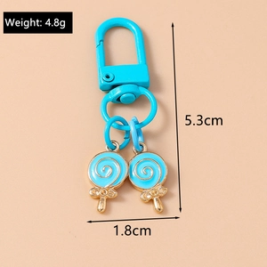 Detail of bright blue lollipop keychain with gold edges and blue lobster clasp