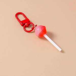 Macro detail of cute red lollipop keychain with lobster clasp on soft beige background