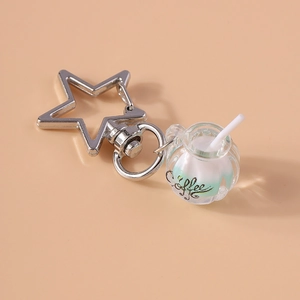 Close-up of a luminous coffee cup keychain with a star-shaped clasp and green liquid