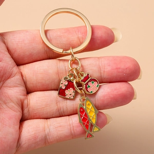 Goldener Schlüsselanhänger mit Koi-Fischen und Glücksbeutel-Anhängern in der Hand