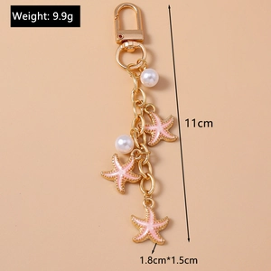 Detailed view of pink starfish keychain with gold plating and white pearls ornaments
