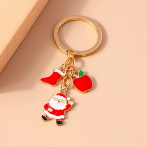 Detail of Christmas keychain with Santa, red boot, and apple charms on a gold ring