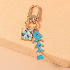 Detail eines goldenen Schlüsselanhängers mit blauem Fischgräten- und Mosaik-Anhänger