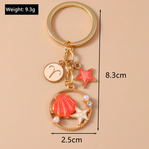 Detail view of gold starfish keychain with Aries charm, pearls and seashell in ring
