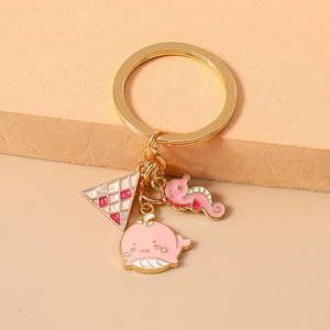 Nahaufnahme der rosa Wal- und Seepferdchen-Emaille-Anhänger an einem goldenen Schlüsselring