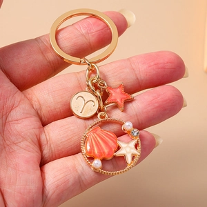 Golden starfish seashell keychain with Aries zodiac sign charm and white pearls
