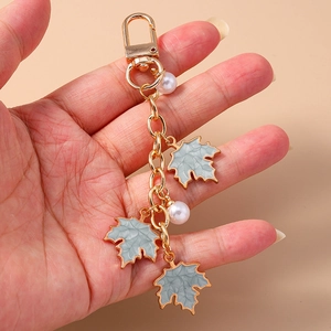 Detail of maple leaf keychain with gold metal chain, marble texture pendants and pearls