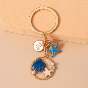 Detail of golden starfish keychain with blue enamel, pearls and Virgo zodiac sign charm